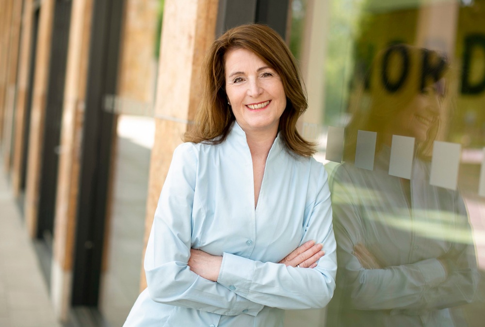 Frau mit Bluse lehnt an Glasfront, LinkedIn-Fotografie von Iris Schmitz